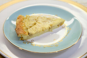 slice of banana clafoutis on a blue and gold plate