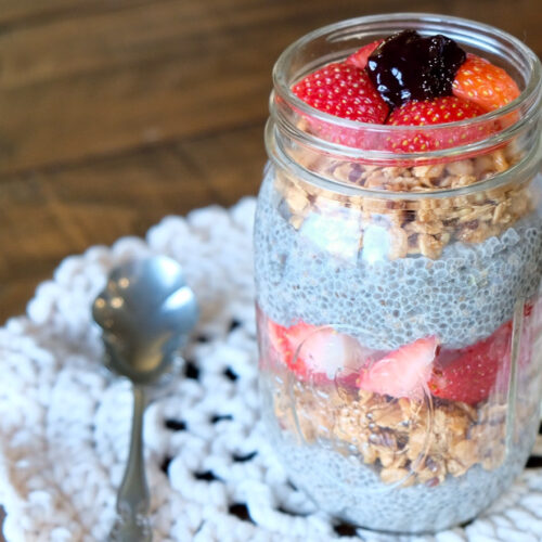 chia pudding layered in a mason jar with fresh strawberries, granola and blackberry preserves