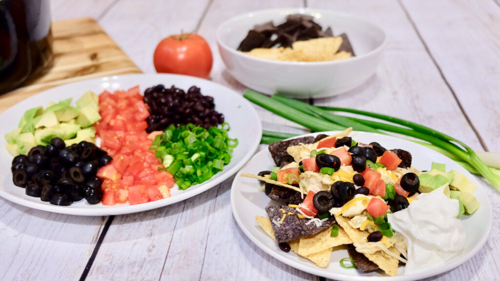 nachos on a plate with some other plates of toppings