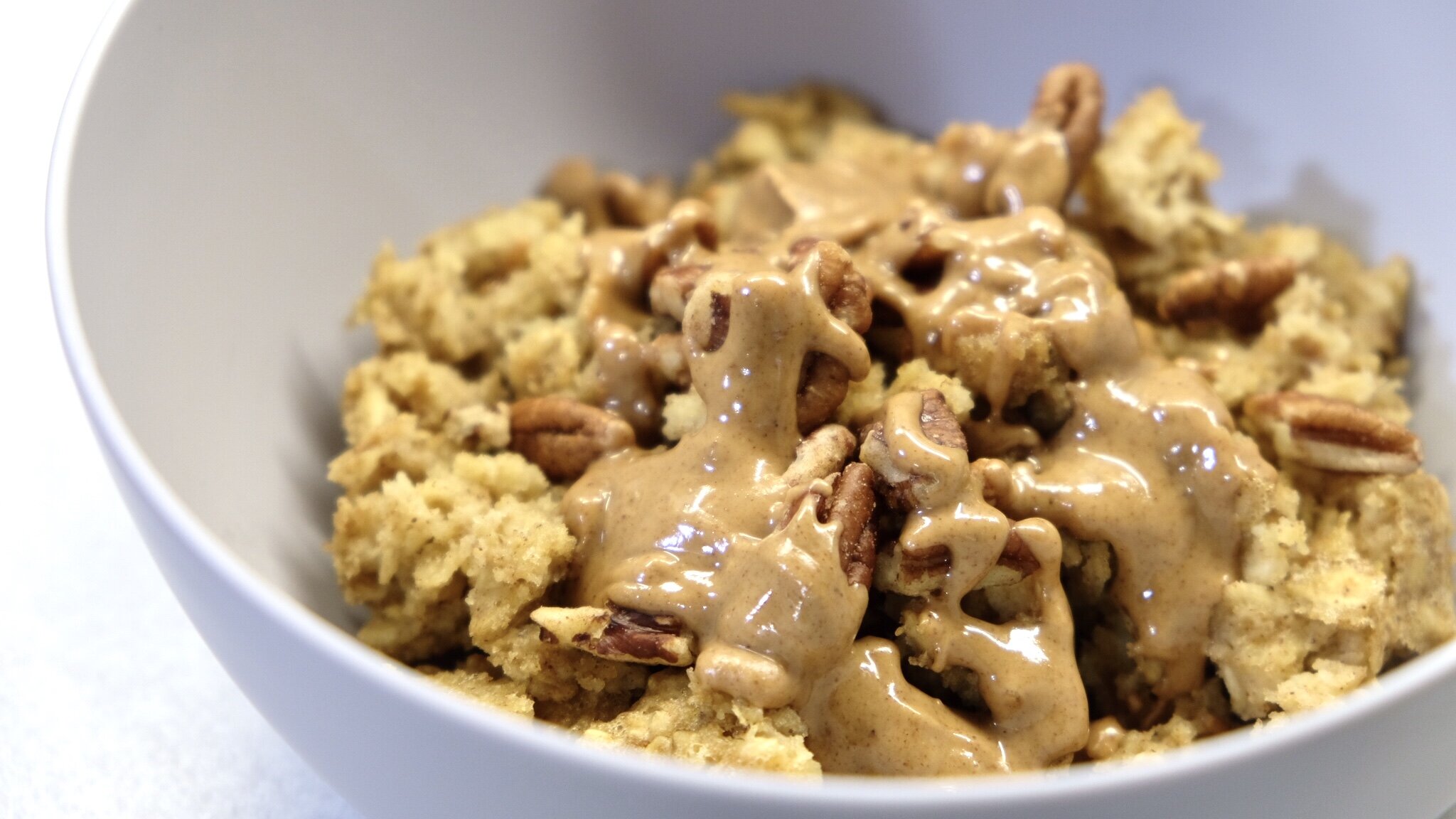 vanilla almond baked oatmeal with drizzled melted almond butter on top in a grey bowl.