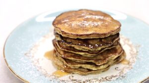 stack of pancakes with syrup on blue and gold plate