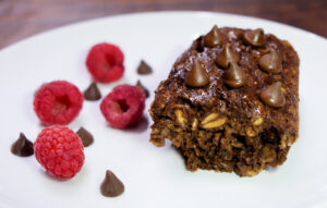 peanut butter chocolate baked oat meal on white plate with raspberries