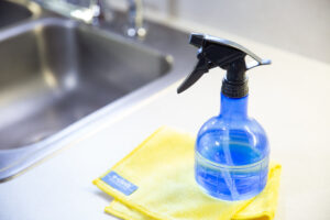 blue spray bottle sitting on yellow ecloth next to kitchen sink