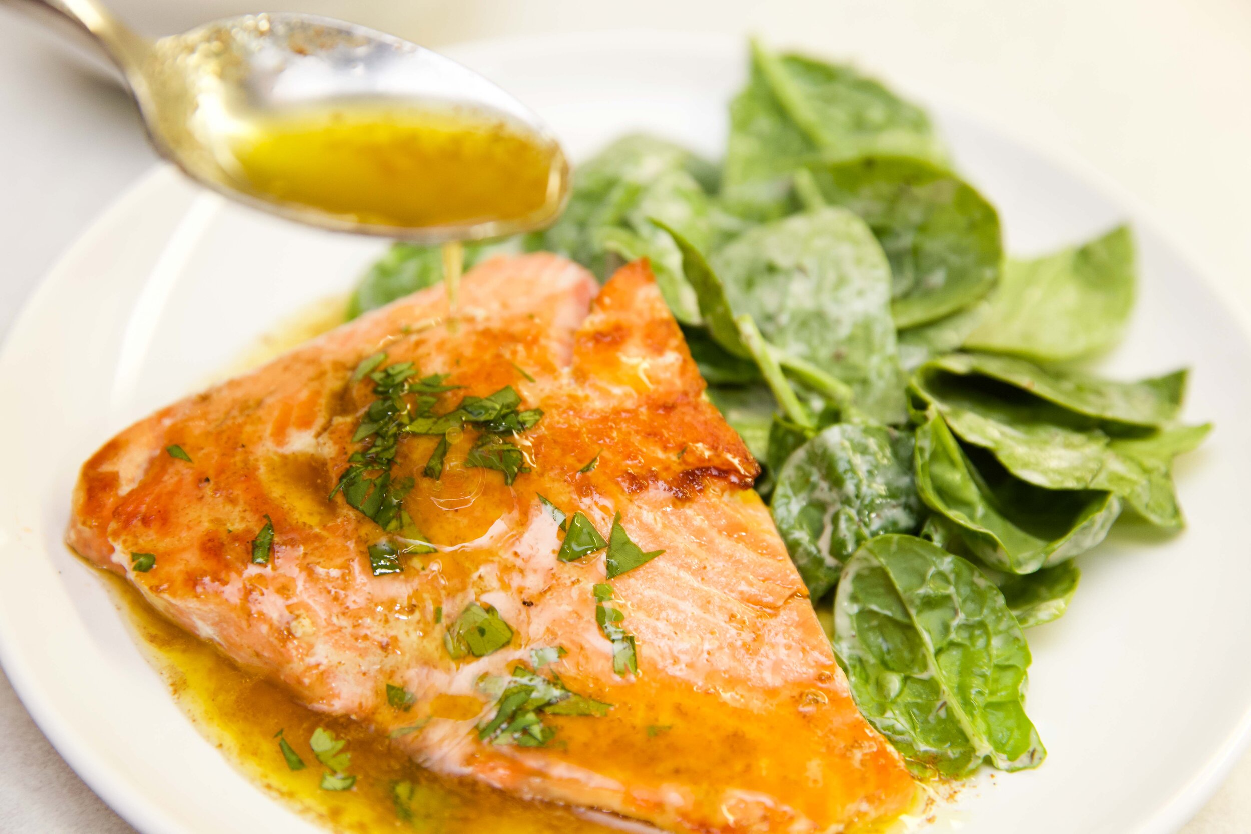 salmon with browned butter lemons sauce and a salad on a white plate