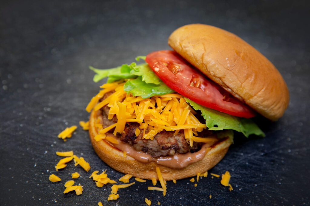 turkey burger with cheese on a black cutting board