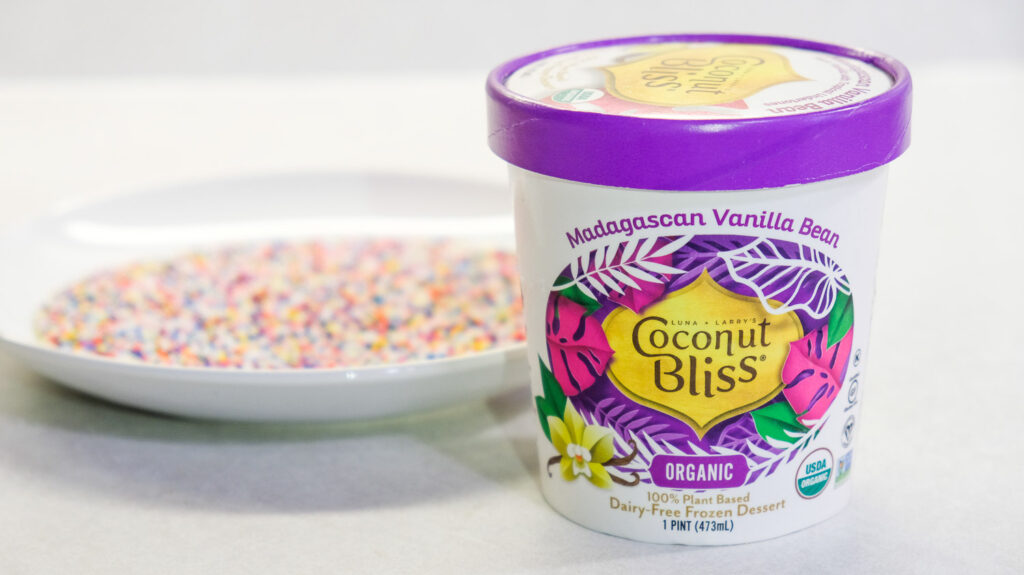 coconut bliss vanilla ice cream carton with a plate of sprinkles in the background