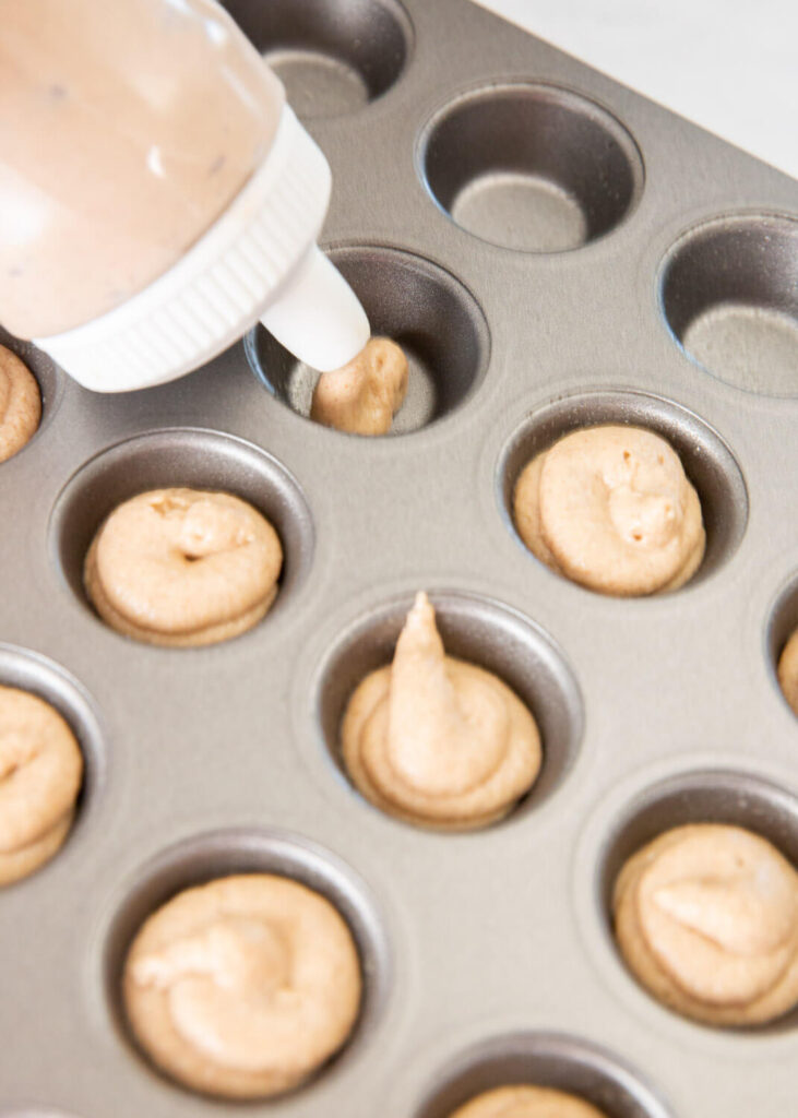 piping applesauce donut bites batter into mini cupcake pan