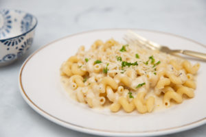 photo of vegan alfredo sauce over pasta on a white plate