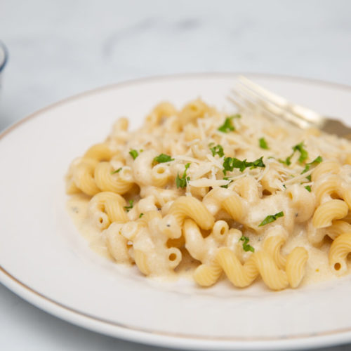 photo of vegan alfredo sauce over pasta on a white plate