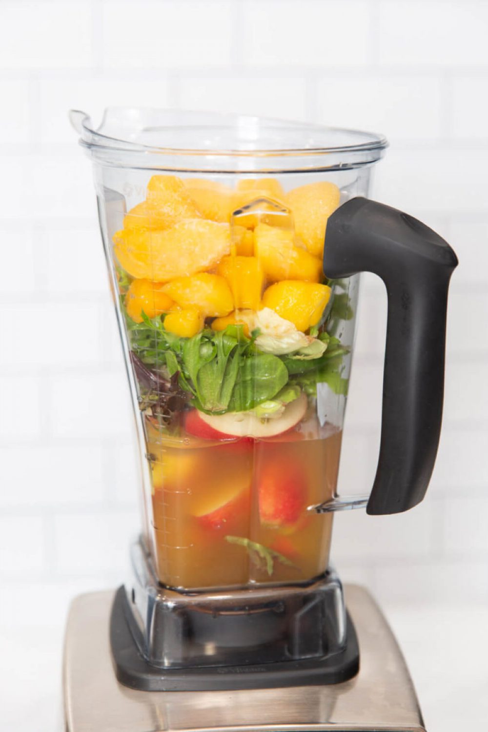 apples, salad greens, mango, peaches and apple juice in a Vitamix blender container